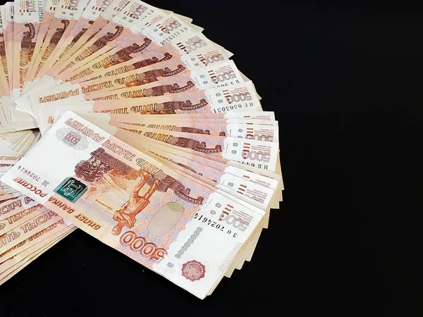 Russian money is fanned out on a black background. Russian banknotes