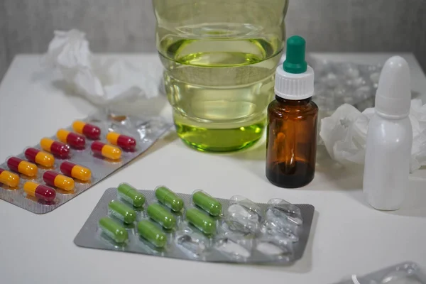 Medicines, medicines, tablets, nose drops, napkins and a glass of water on the bedside table in modern apartments. Concept of home treatment of coronavirus