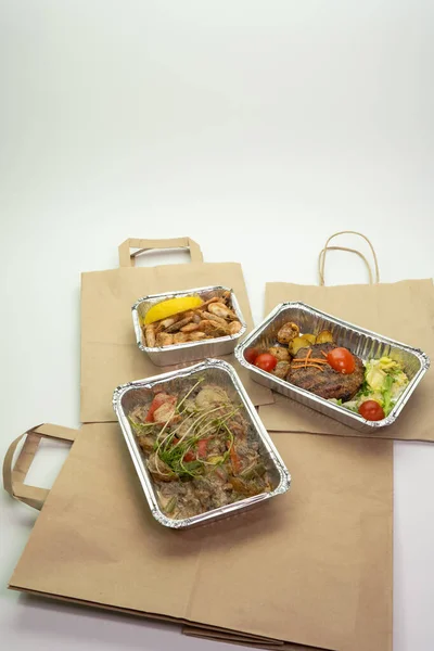 Delivery of delicious healthy food in foil boxes. Concept of food delivery in quarantine, self-isolation