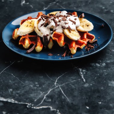 Muz dilimli Viyana waffleları, çikolata kırıntıları serpiştirilmiş krema, yakın plan, kopyalama alanı