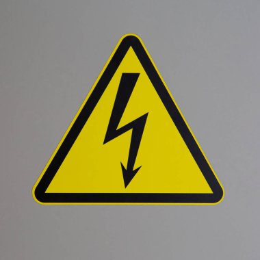 Gri arkaplandaki uyarı işaretinde elektriksel tehlike sembolü