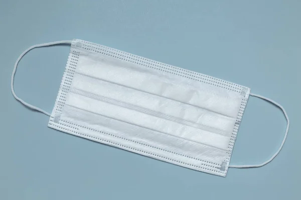 Surgical mask with rubber straps. A three-layer surgical mask for covering the mouth and nose. Bacterial mask procedure. Concept of protection.