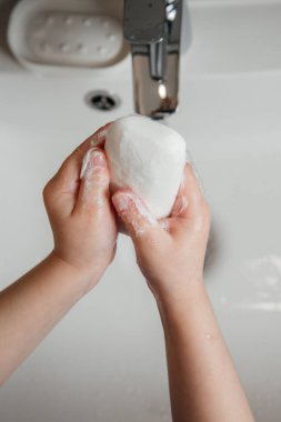 Bebek ellerini lavaboda sabunla kalite olarak yıkıyor.