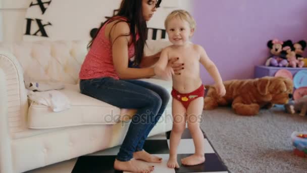 Молодая женщина одевает ребенка в костюм Человека-паука — стоковое видео