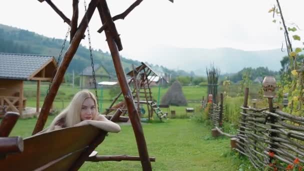 Νεαρή γυναίκα να ξεκουραστείτε για μεγάλο woode swing — Αρχείο Βίντεο