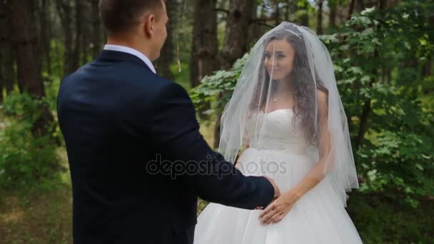 Bruidegom opent het gezicht van de bruid haar sluier verhogen — Stockvideo