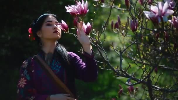 Молодая азиатка позирует в цветущей магнолии — стоковое видео