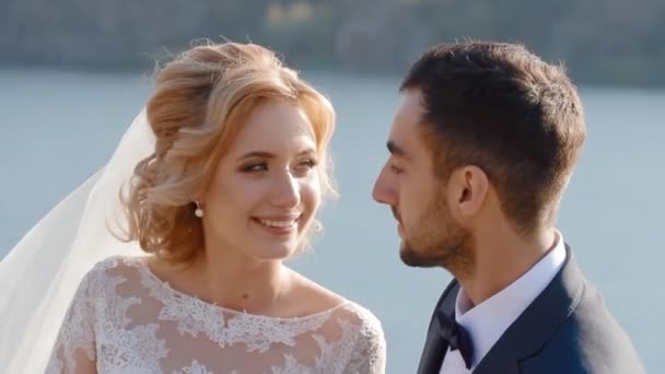 Menyasszony és a vőlegény, a folyó közelében pózol — Stock videók