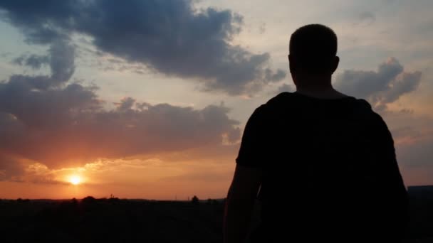 Turysta z torbą przychodzi na wzgórzu na zachodzie słońca — Wideo stockowe