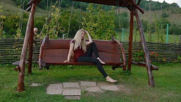 Giovane donna si riposa sul grande swing boschivo — Video Stock