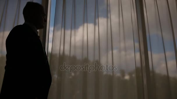 Ο άνθρωπος στο κοστούμι με τα πόδια μπροστά από το μεγάλο παράθυρο — Αρχείο Βίντεο