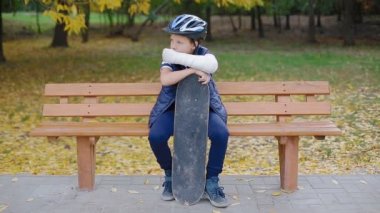 Kırık kolu ile paten oturan beyaz çocuk