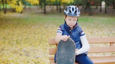 Kırık kolu ile paten oturan beyaz çocuk