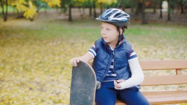 Kırık kolu ile paten oturan beyaz çocuk