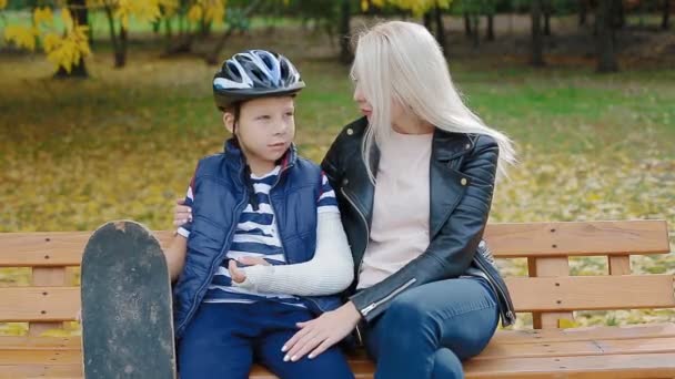 Mother and son sitting on the bench in the park — Stock Video