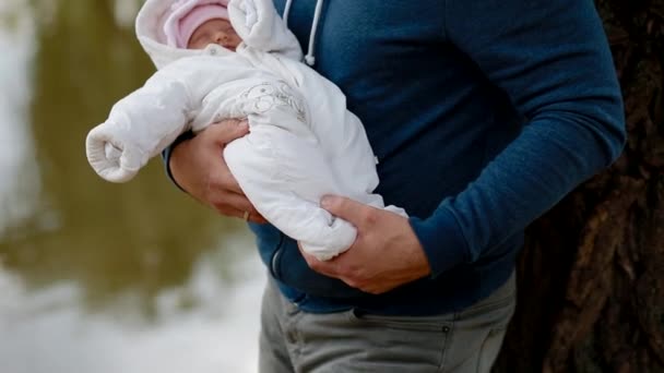 Молодий чоловік тримає свою новонароджену дочку на руках — стокове відео