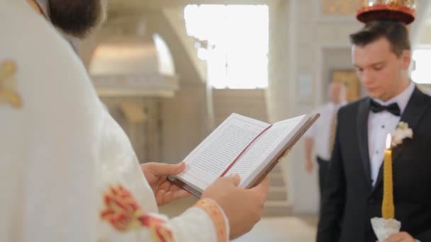 De priester leest een gebed bij het huwelijk van een jong koppel — Stockvideo