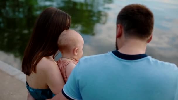 Familia joven con un niño pequeño cerca del río — Vídeos de Stock