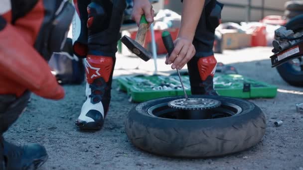 KYIV, UKRAINE - 27 JUILLET 2019 : Un homme répare une roue de moto avec un marteau et un tournevis — Video