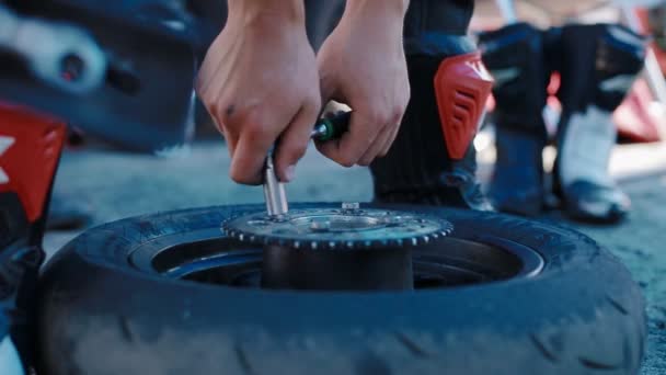 A man with his bare hands unscrews the bolts on a motorcycle wheel — Stock Video