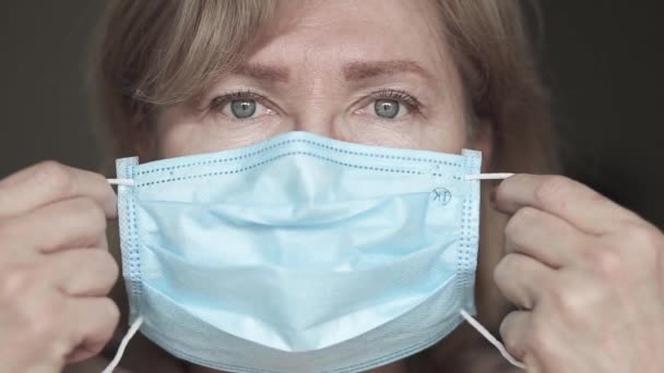 Weiße Seniorin setzt medizinische Maske auf ihr Gesicht — Stockvideo