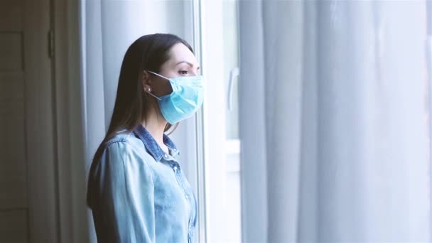 Young caucasian woman with medical mask coming to the window. — Stock Video