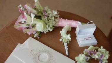 Düğün buketi nişan aksesuarlarıyla birlikte masada duruyor.