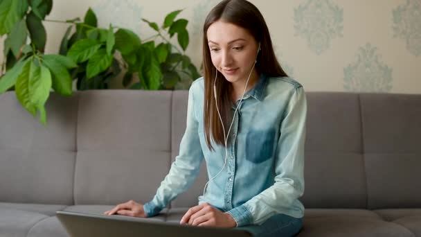 Morena de cabelos longos em ondas de fones de ouvido e conversas no laptop — Vídeo de Stock