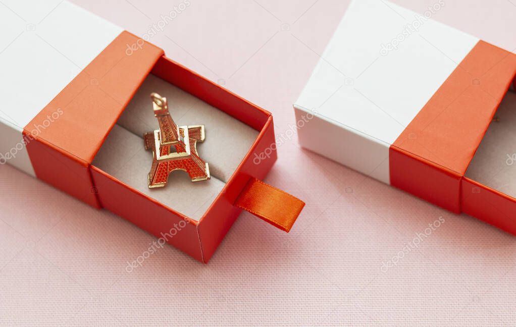 in the open gift box lies the eiffel tower on a pink background