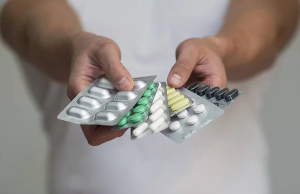 Pilulky v balíčku v rukou muže na lehkém pozadí — Stock fotografie