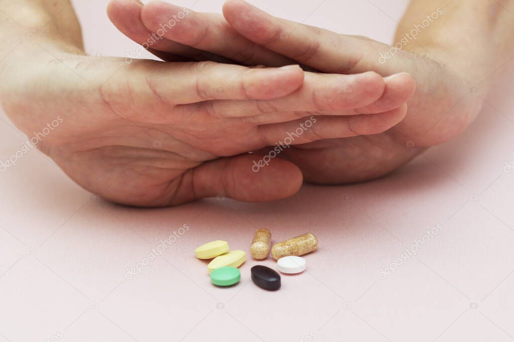 man refuses pills, pills on the table, health, medicine, pink background