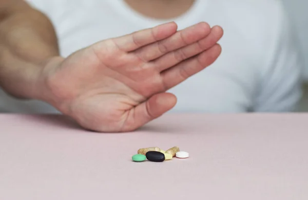 Adam hapları reddediyor, masada haplar, sağlık, ilaç, pembe arka plan