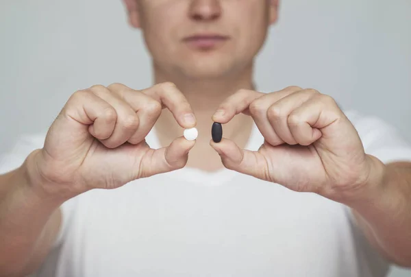 Siyah ve beyaz haplar, bir adam elinde hapları seçme şansı verir.