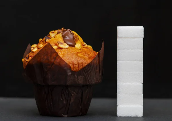 sugar level next to the cupcake, cubes sugar stacked on top of each other, the amount of sugar in the dish