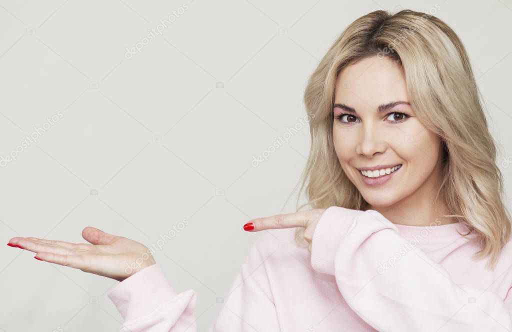 funny beautiful blonde girl grimaces at the camera, she playfully behaves, pink background