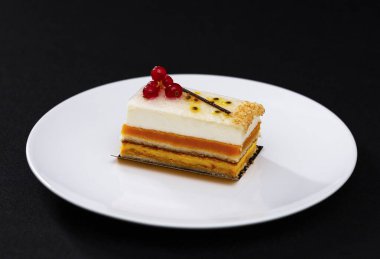 Beyaz kremalı ve kırmızı üzümlü çok katmanlı güzel pasta, beyaz tabakta, tatlı servisi.