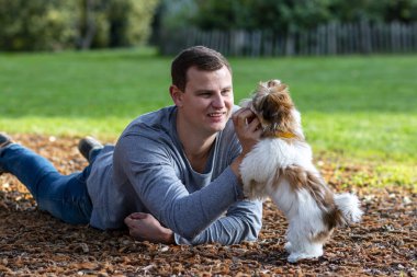 Bir adam, parkta külahta debelenirken güzel bir köpek yavrusuyla bir hayvanla etkileşime giriyor.