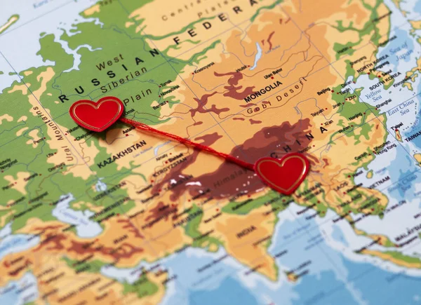 iki kırmızı kalp bir dünya haritasında kırmızı bir ipliğe bağlı