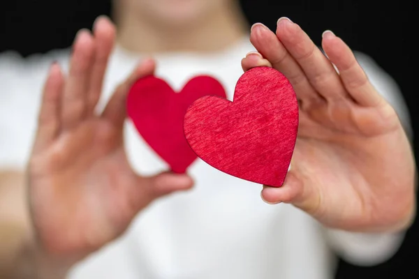 Adam kırmızı kalbi elinde tutuyor. Hafif giysilerin arka planında.