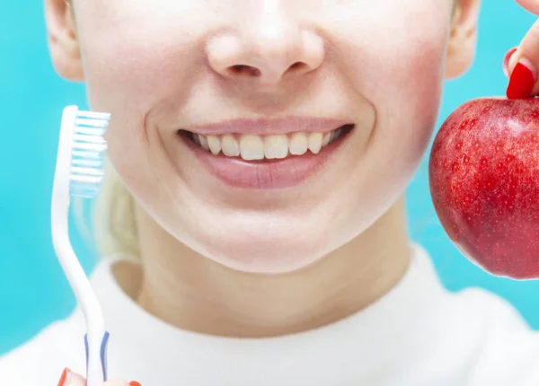 Niña sostiene una manzana y un cepillo de dientes, cuidado dental — Foto de Stock