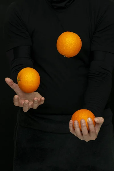 Erkek eli, arka planda taze portakallarla hokkabazlık yapar.