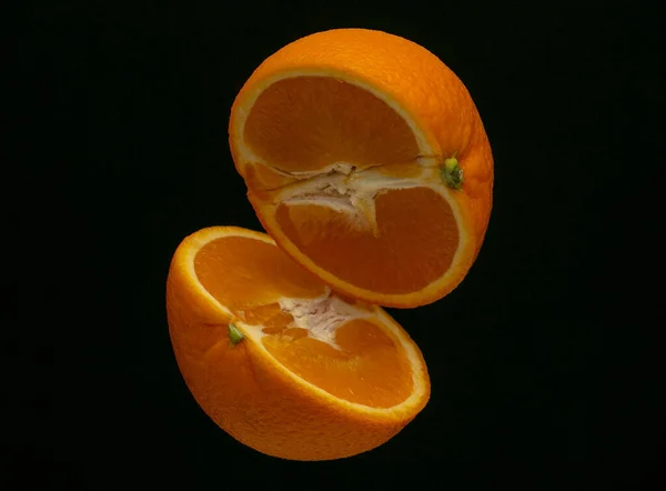 Belle coupe orange juteuse en deux s'élève sur un fond noir — Photo