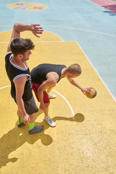 Couple of guys playing basketball outside