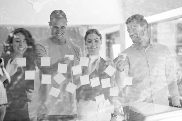 бизнес, карьера, планирование, управление и человеческая концепция - счастливая творческая команда, пишущая на стеклянной доске в офисе
