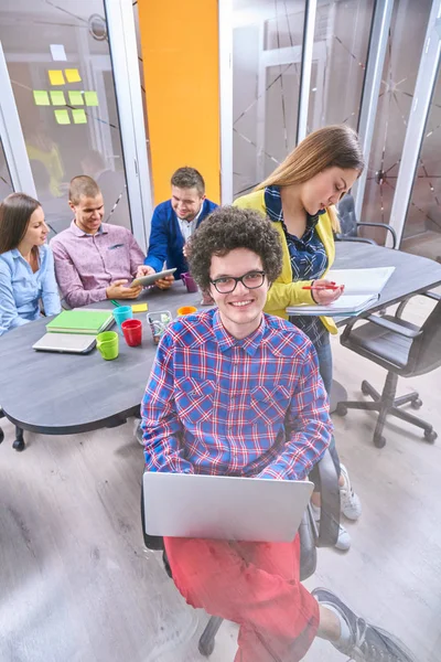 Portrait of startup group of creative people having a meeting with a laptop in a modern office. Business people having relaxed conversation over new project in coworking space