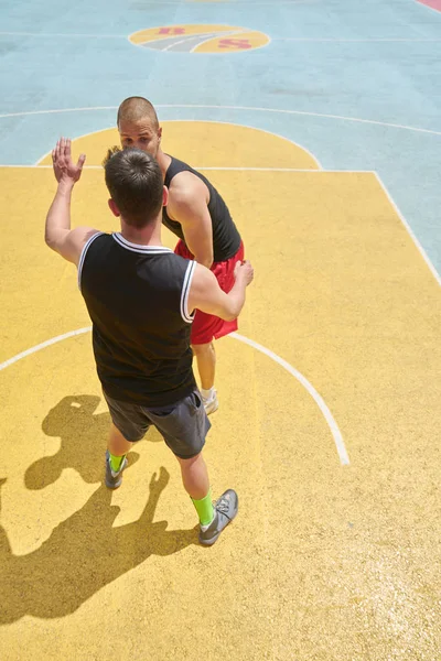 Couple of guys playing basketball outside