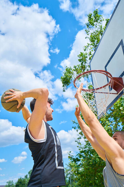 Couple of guys playing basketball outside     