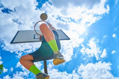 Mavi gökyüzü karşı sepet içine topu atma basketbolcu 