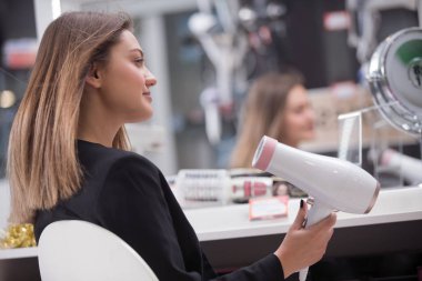 Saç bakım. Güzel uzun saçlı kadın elektronik mağazasında saç kurutma