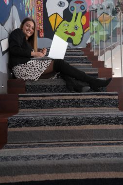 Kız ofiste merdivenlerde oturan dizüstü bilgisayar ile 